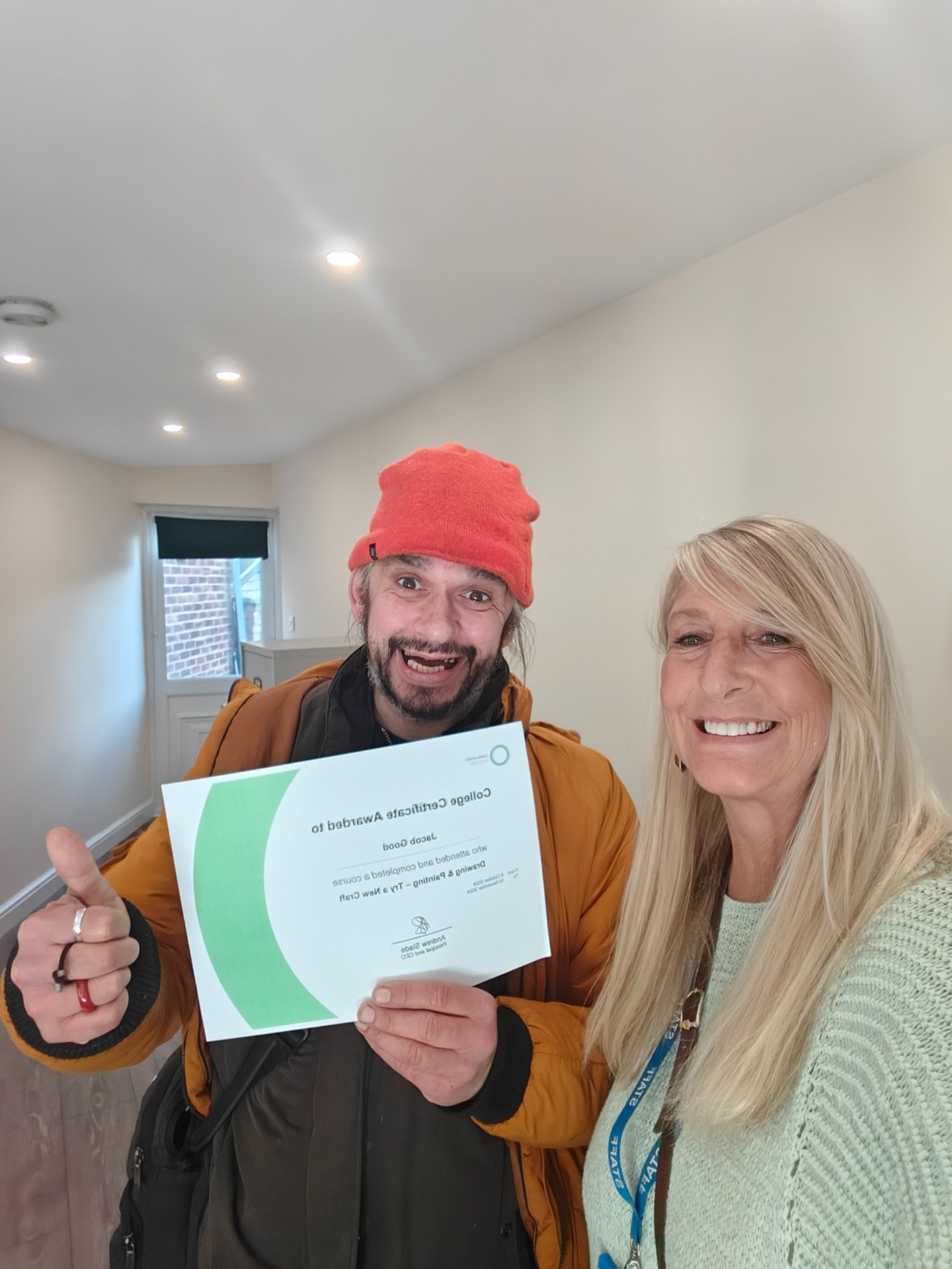 A resident celebrating a training certificate with a Sleapcross House staff member