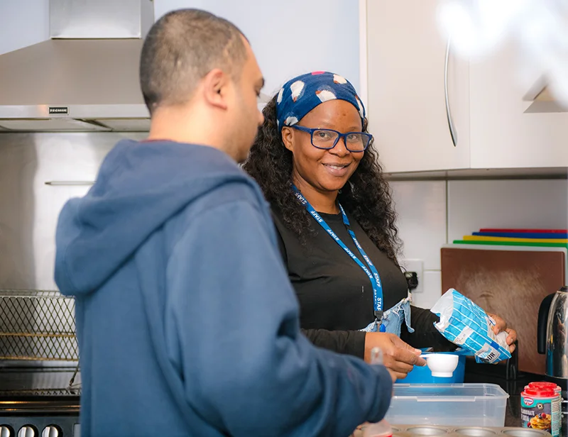 A Sleapcross House staff member supporting a resident with cooking in the kitchen